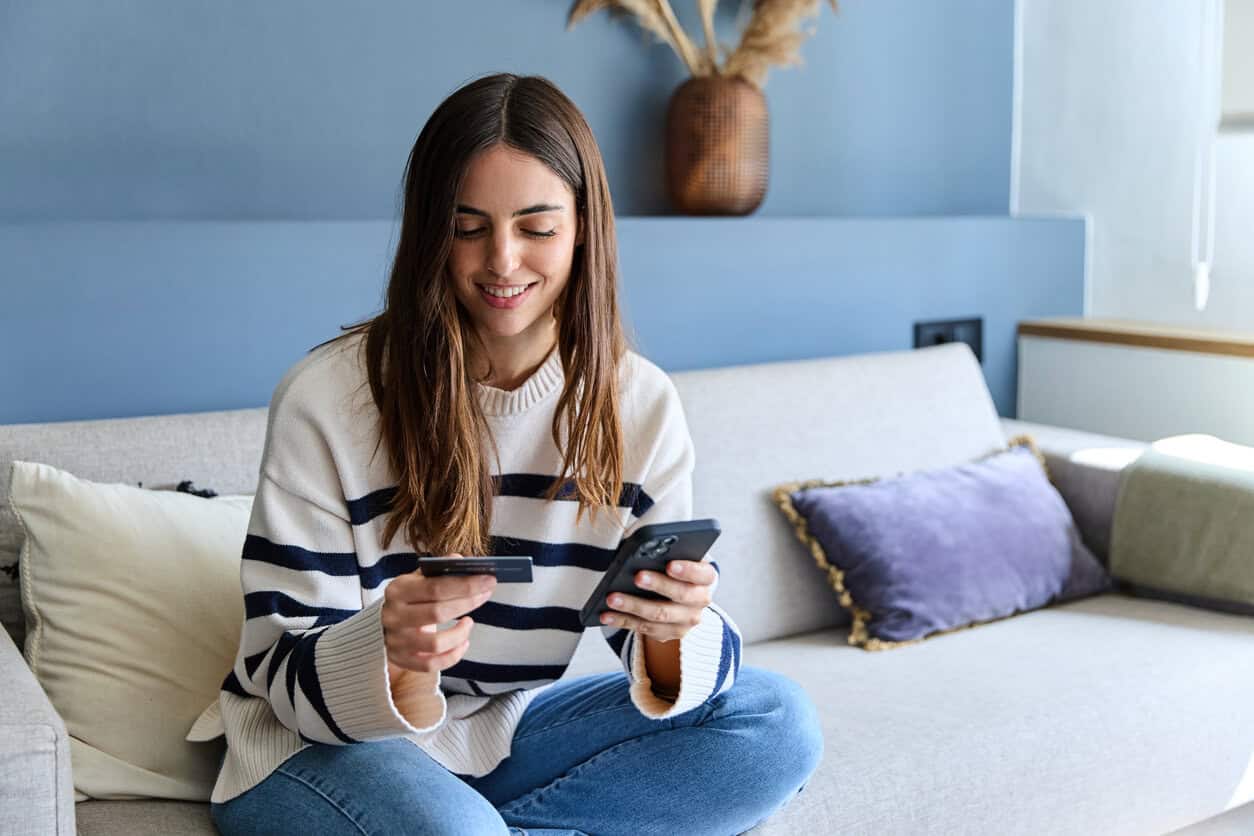 A woman checking credit card program acronyms on her phone.