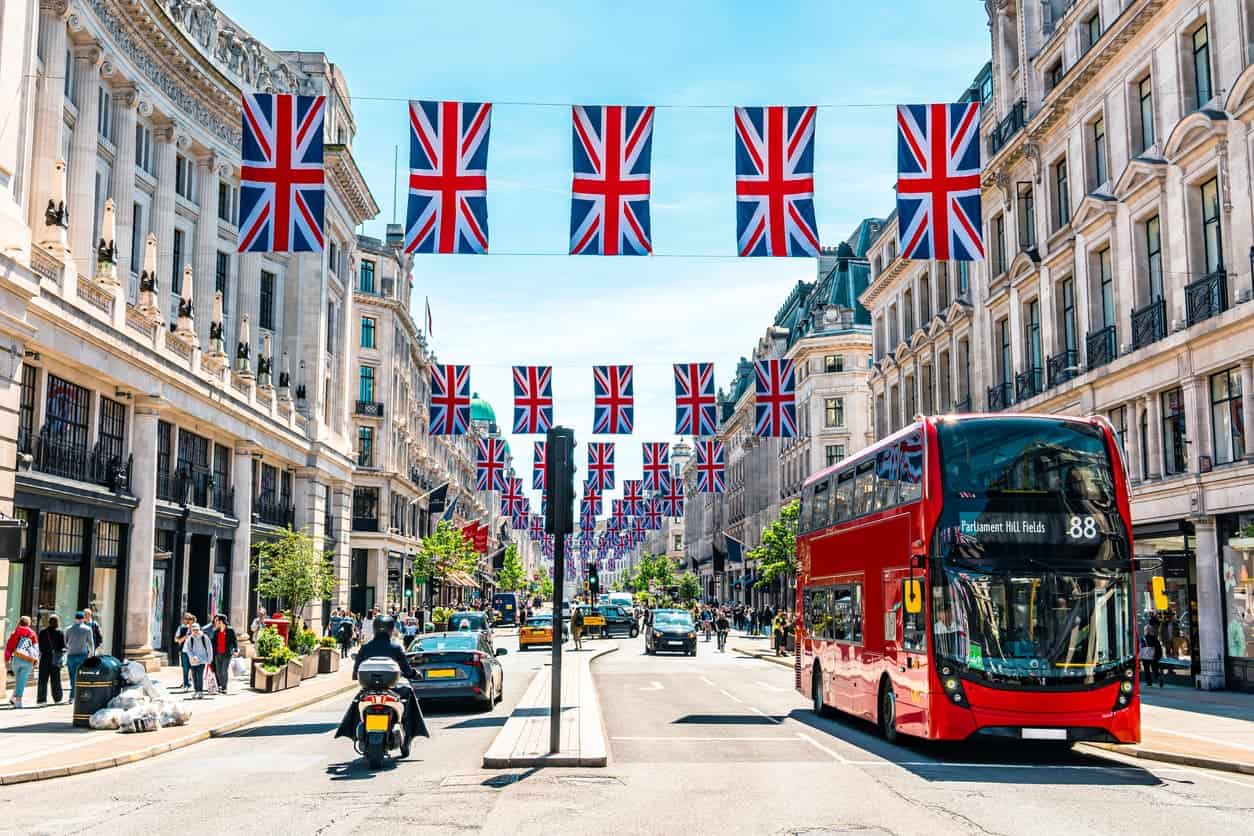Regent Street in London decorated with Union Jack flags and a red double-decker bus.