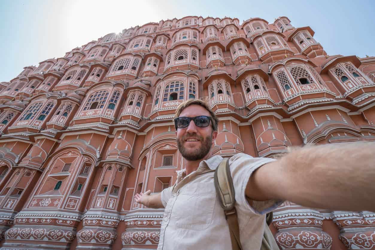 Tourist taking a selfie in front of the Hawa Mahal palace in Jaipur, India.