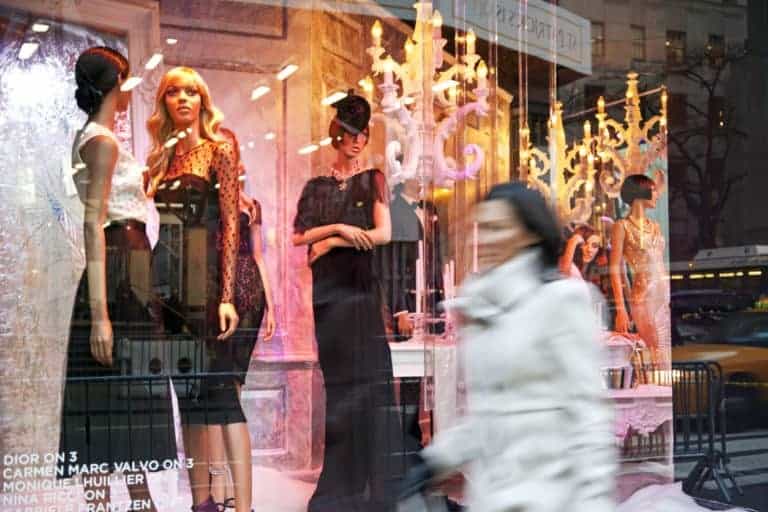 A woman walks along the window display of Saks Fifth Avenue with haute couture by Dior, Carmen Marc Valvo, Monique Lhuillier and Nina Ricci.