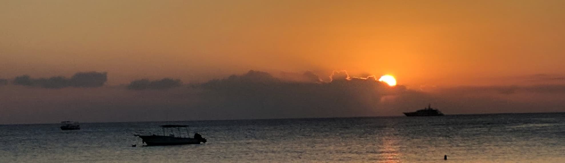 Sunset over the ocean with boats silhouetted against the horizon during golden hour seascape