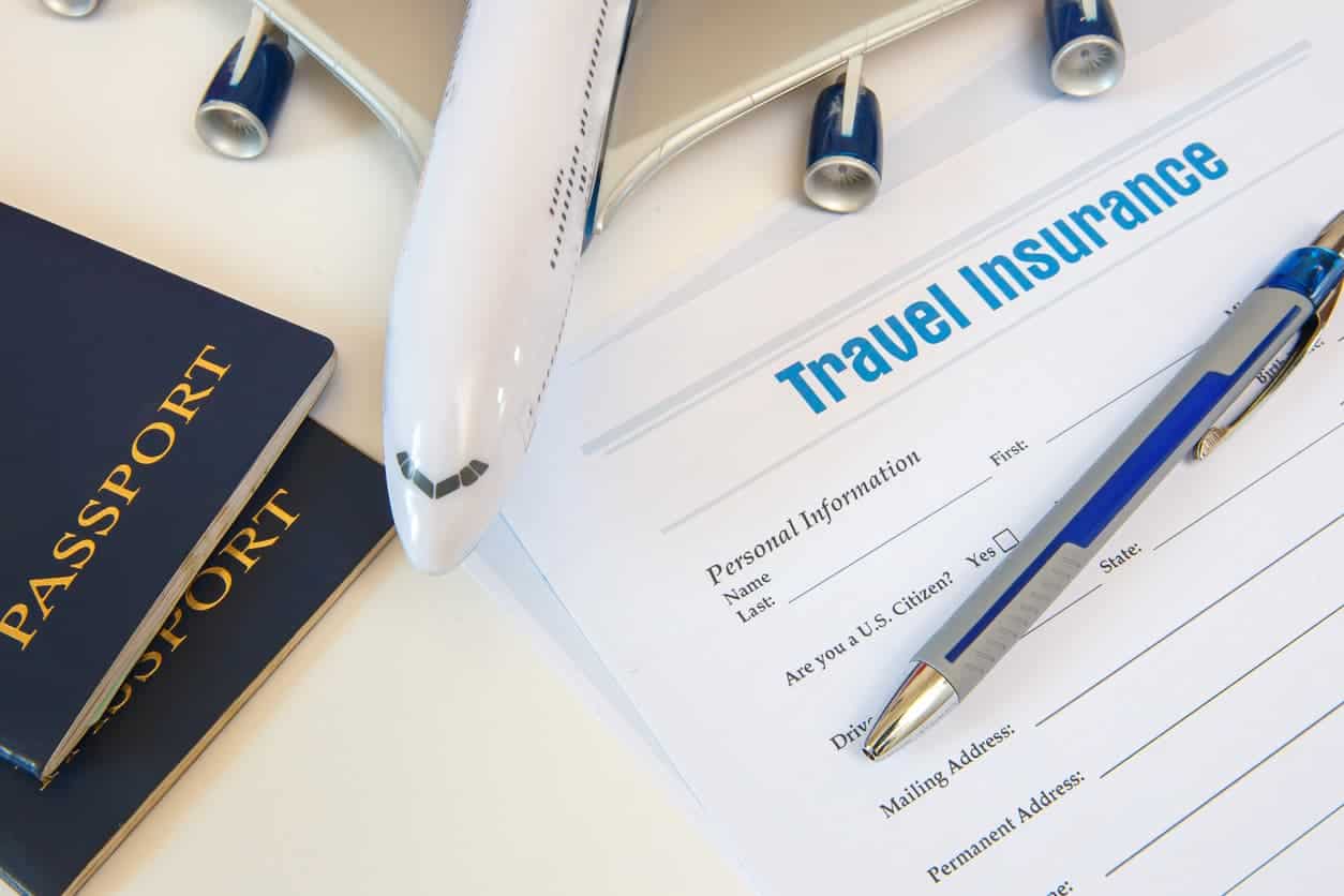 Travel insurance form with passport and airplane model on desk
