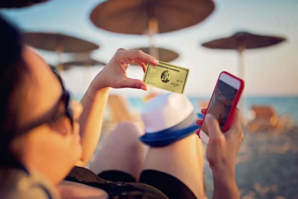 Woman is shopping online using her credit card on the beach