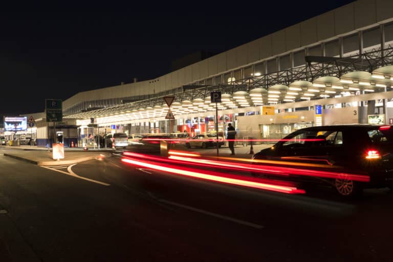 Frankfurt, Germany - February 27, 2016: Entrance departure terminal hall of Frankfurt International airport. Some taxis, arriving cars and passengers in the foreground. Long exposure shot with motion blurred tail lights. Frankfurt am Main Airport is a large international airport located in Germany, 12 km off the city centre of Frankfurt am Main. It is the largest airport in Germany and serves nearly all international destinations in the world.