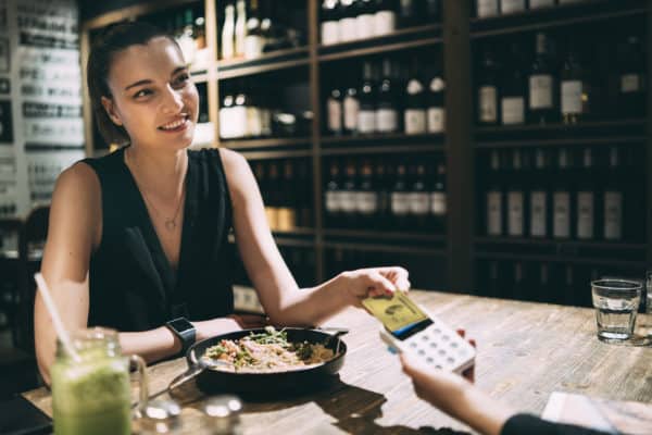 Smiling woman using credit card in winery