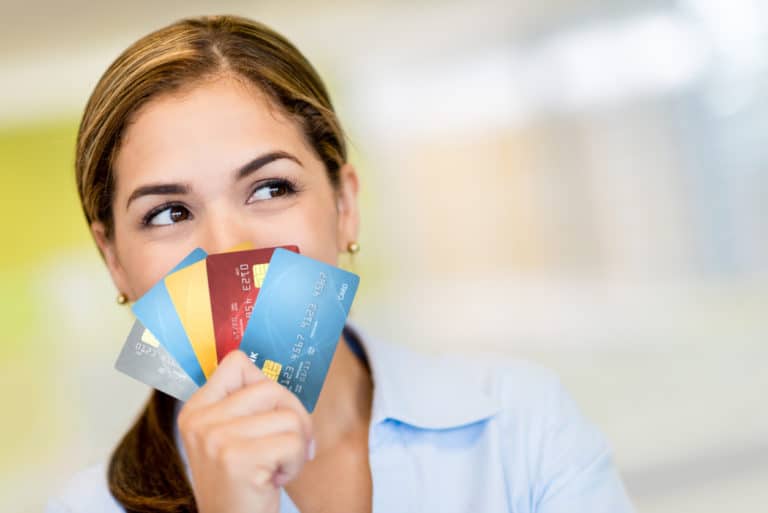 Woman holding credit cards covering her smile to help symobolize getting chase cards within the chase bonus rules