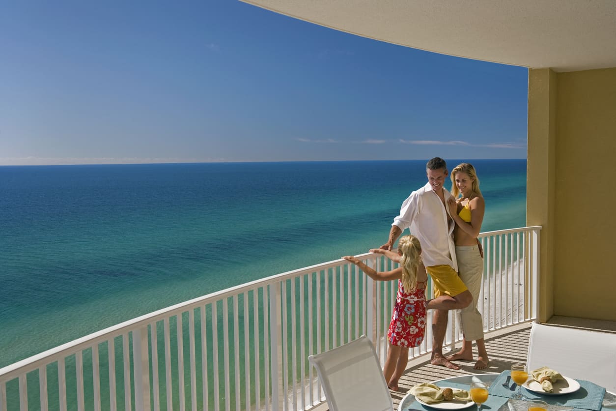 Family of Three On Hotel Balcony Overlooking Ocean