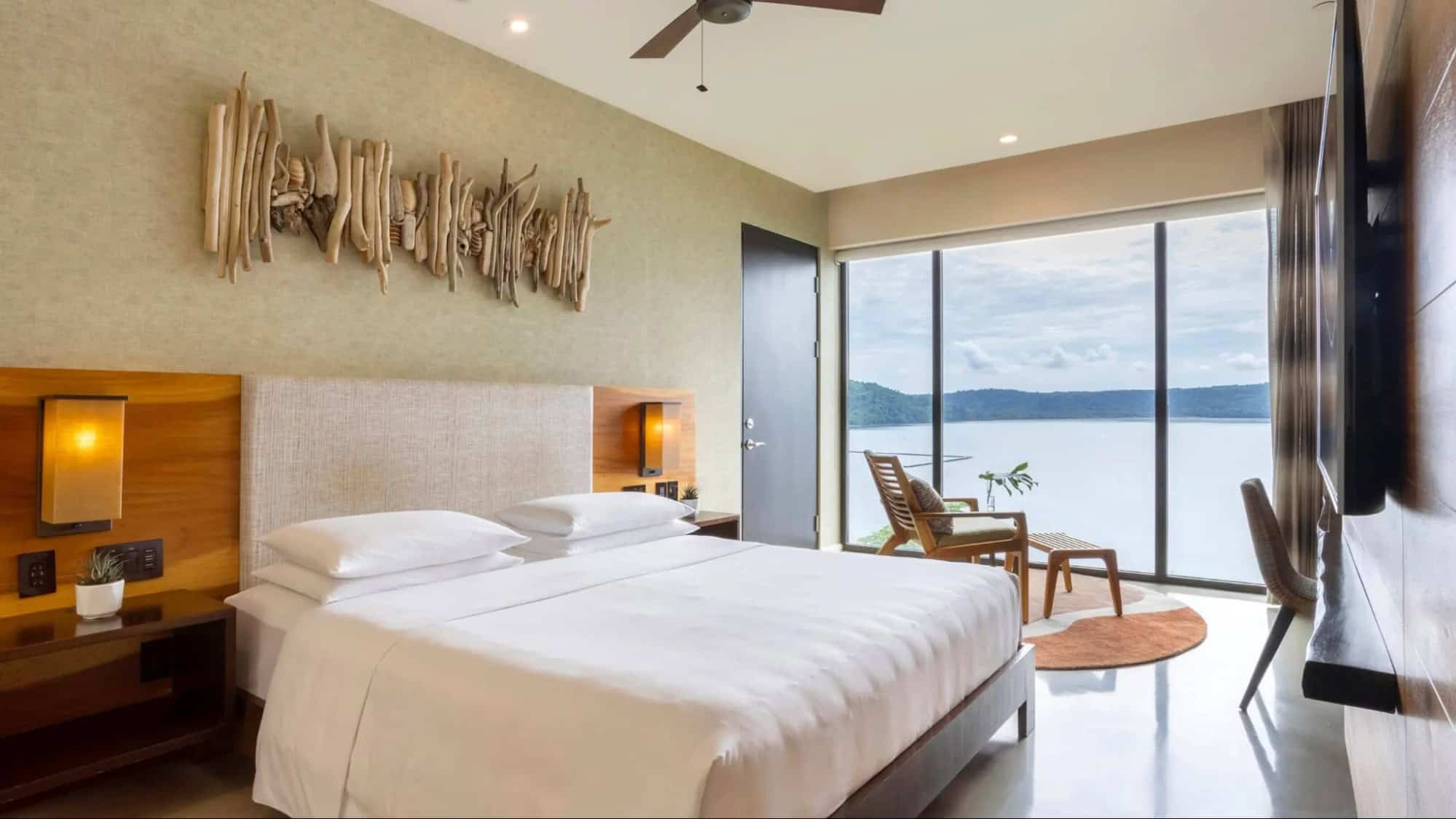 Lake-view guest room at Andaz Costa Rica Resort at Peninsula Papagayo featuring a king bed, natural wood accents, modern tropical décor, and floor-to-ceiling windows overlooking the water
