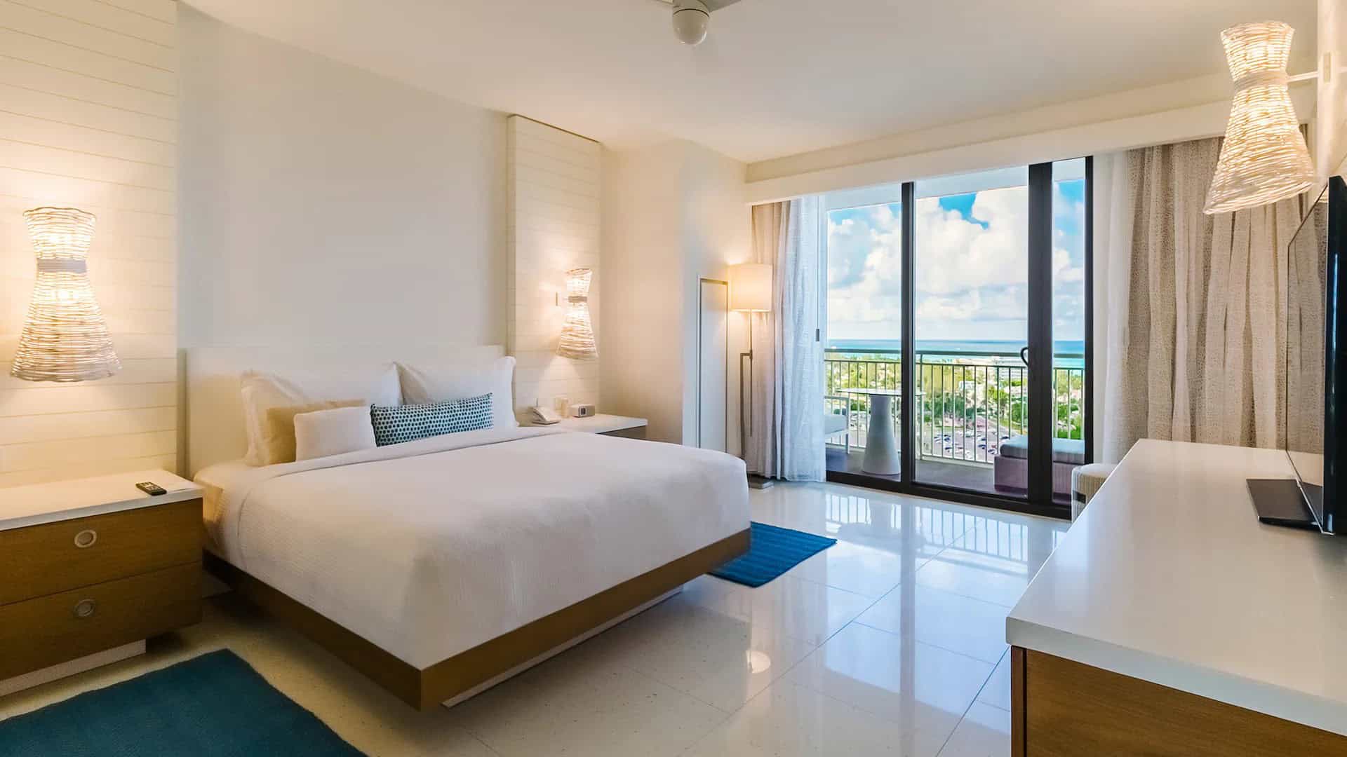 Ocean-view guest room at Grand Hyatt Baha Mar in the Bahamas with a king bed, modern island decor, floor-to-ceiling windows, and a private balcony overlooking the resort and sea