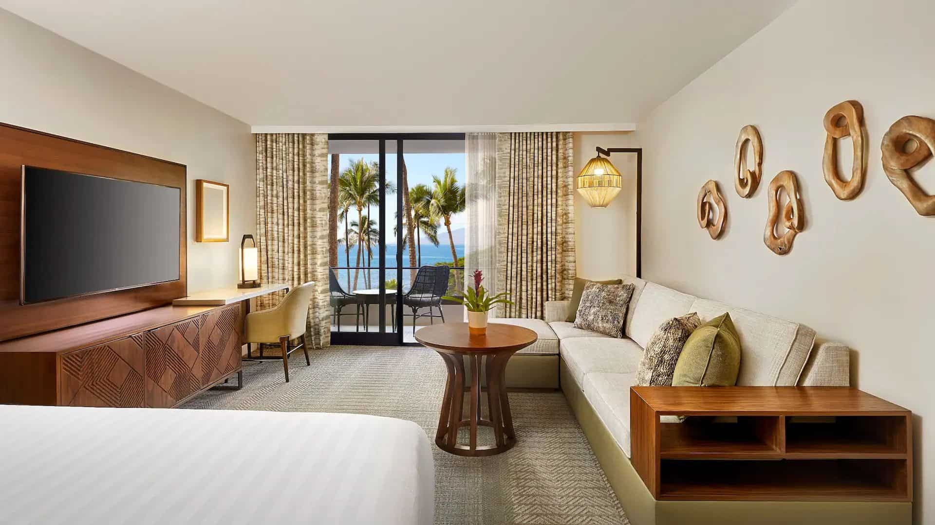 Ocean-view guest room at Hyatt Regency Maui Resort and Spa featuring a seating area, modern island decor, and balcony overlooking palm trees and the Pacific Ocean