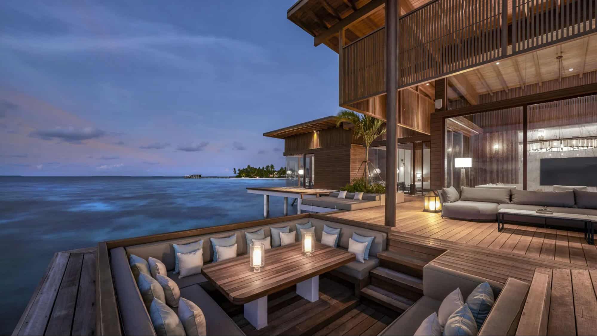 Overwater villa at Park Hyatt Maldives Hadahaa at dusk with wooden deck seating, ocean views, and modern luxury architecture