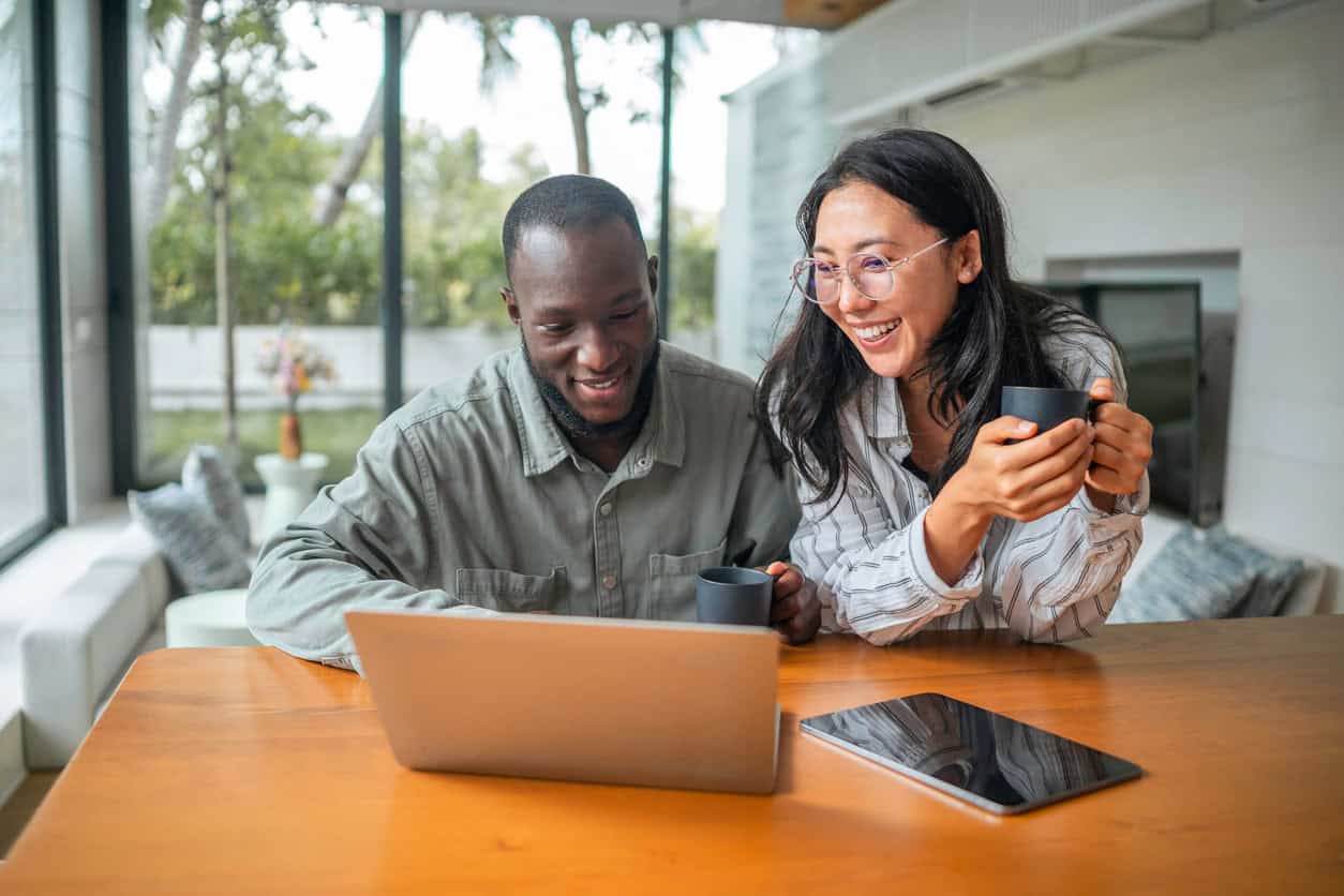 Couple using a laptop to book U.S. all-inclusive resorts with points and miles while enjoying coffee at home