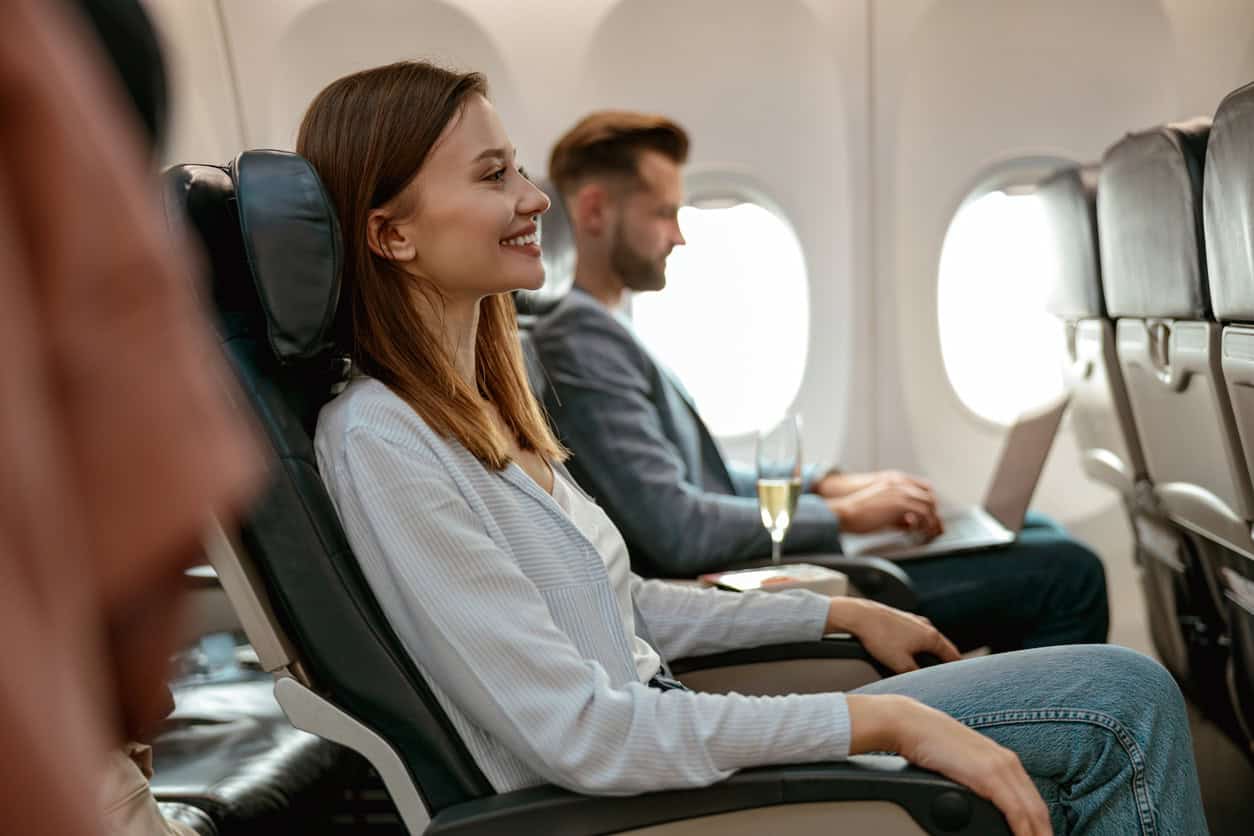 Airline passengers seated comfortably in an airplane cabin during flight, enjoying extra legroom and inflight comfort.