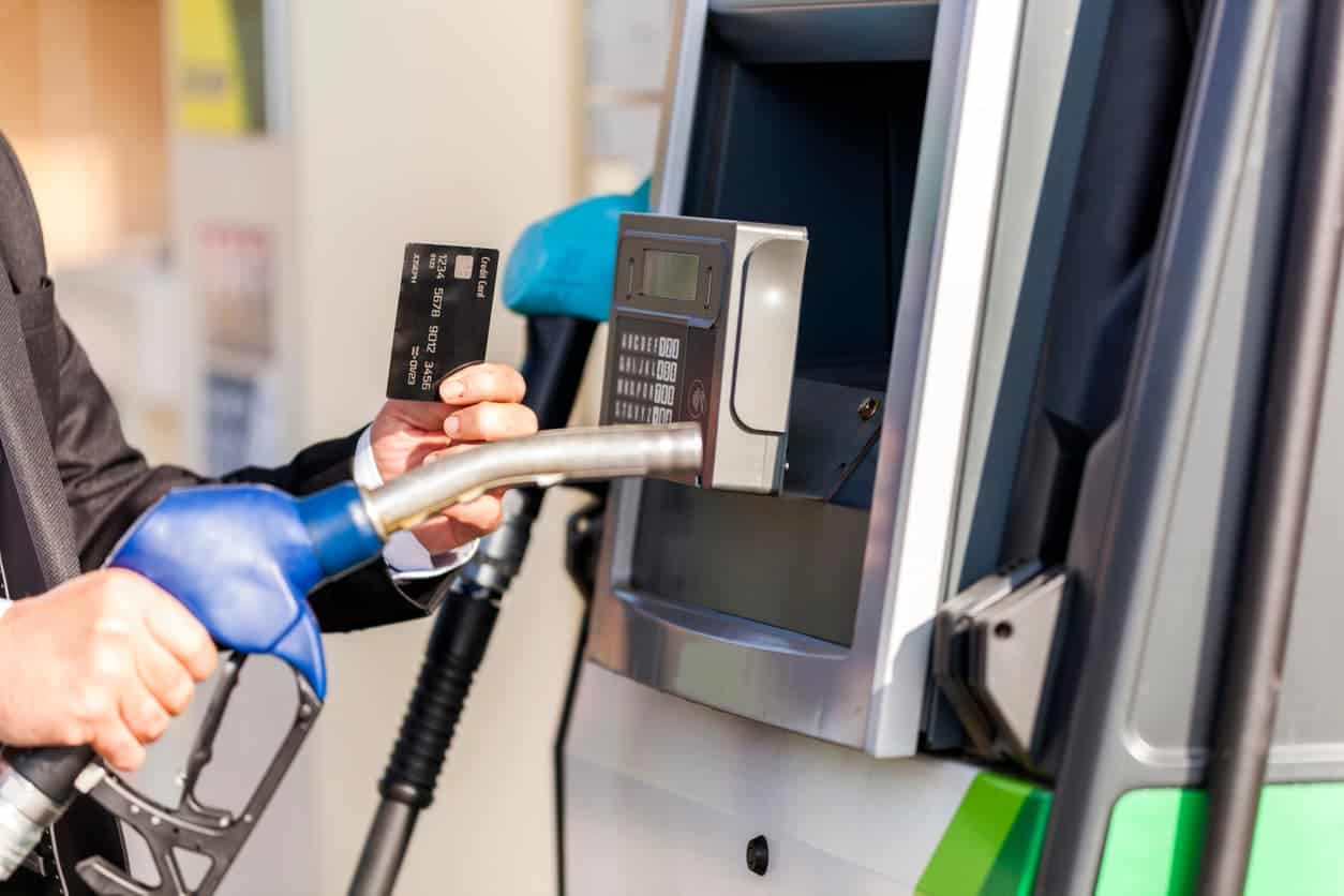 Man holding credit card and fuel nozzle at gas station pump