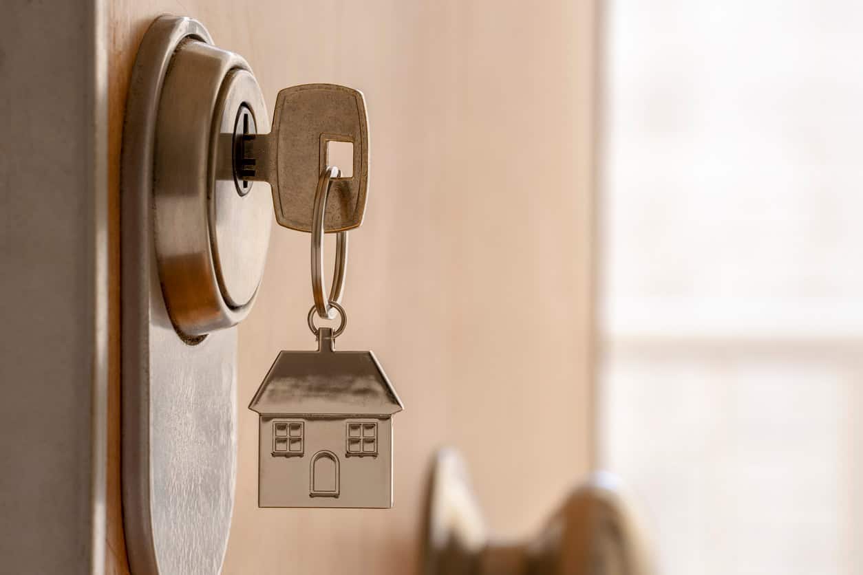 Key in door lock with house-shaped keychain symbolizing home ownership or new property access