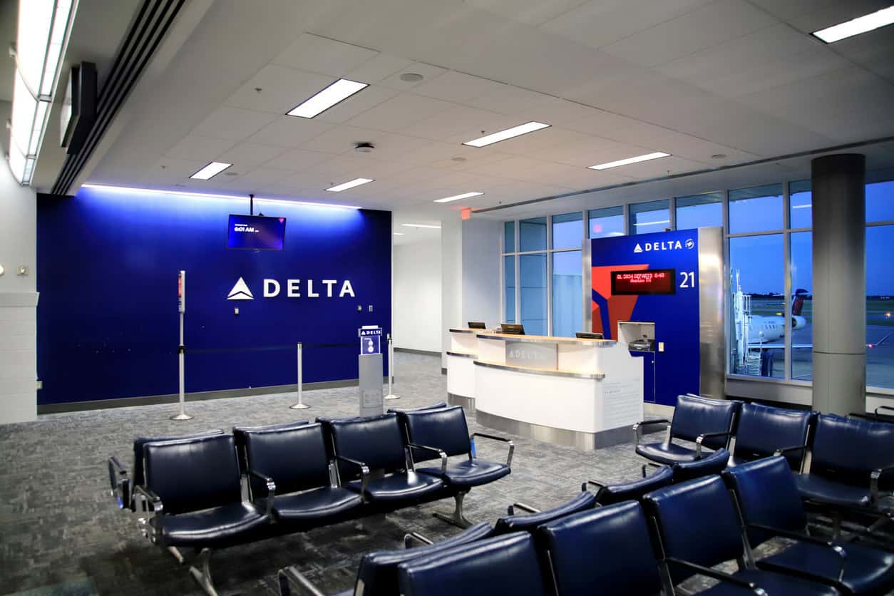 Delta Air Lines boarding gate area with seating and check-in counter at an airport terminal.
