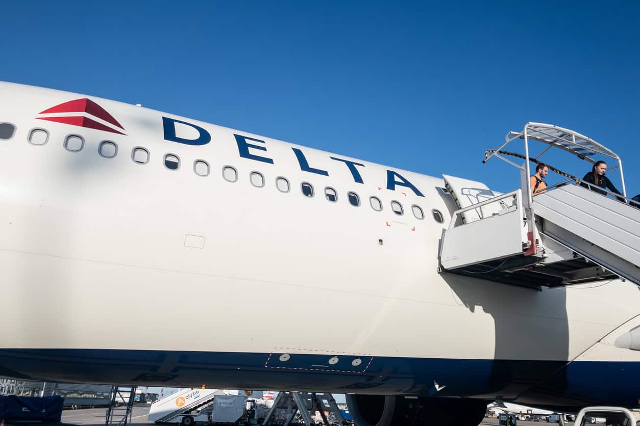 Passengers boarding a Delta Air Lines aircraft via mobile stairs on the tarmac.