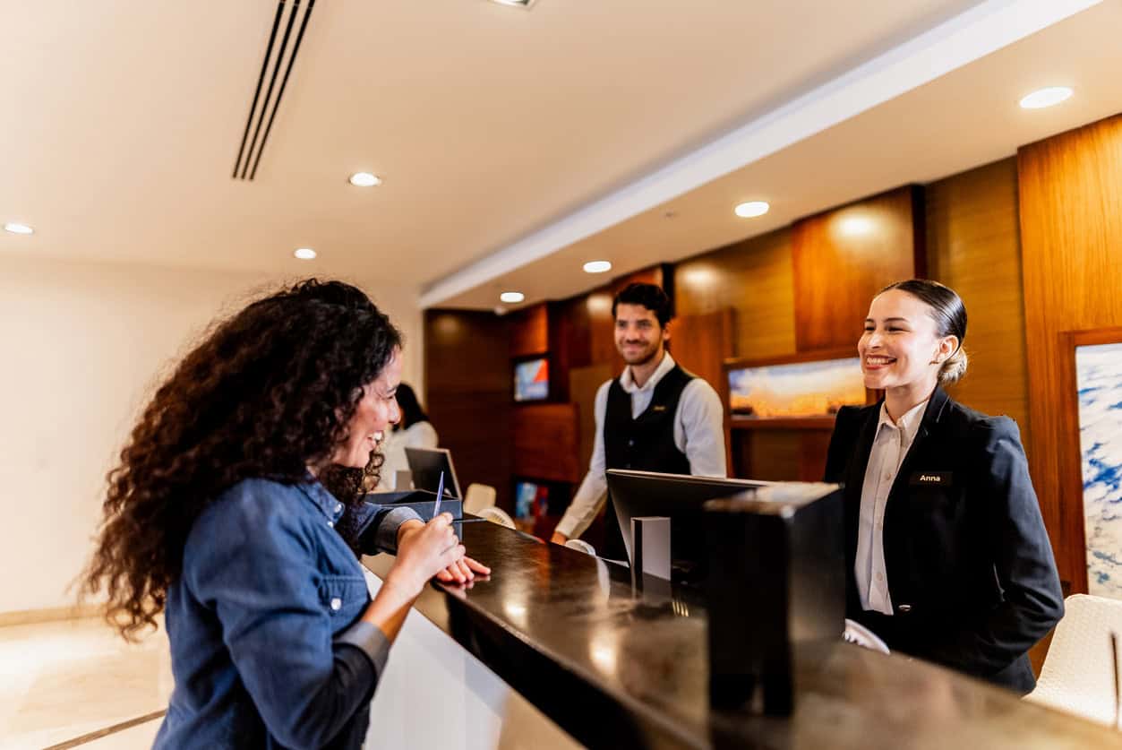 Traveler checking in at a hotel front desk, using a credit card to earn travel rewards points