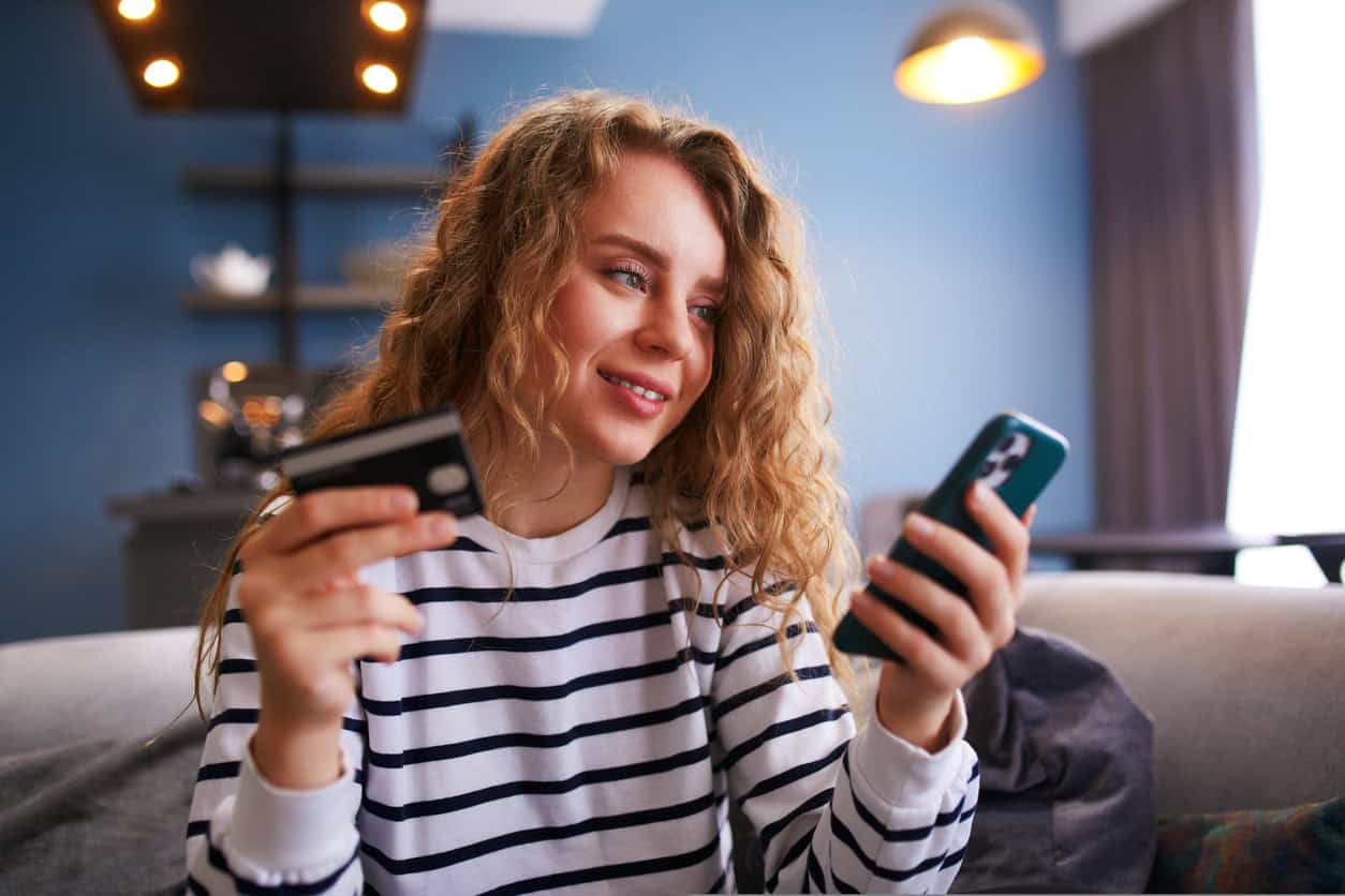 Woman using a credit card and smartphone to shop online and earn rewards points