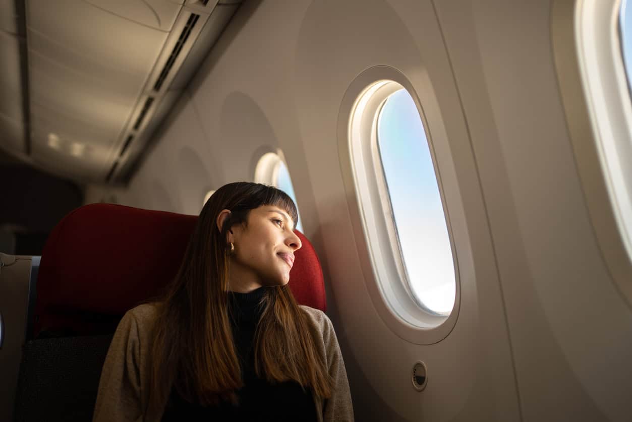 Female traveler seated on an airplane looking out the window during a flight, enjoying the view from her seat