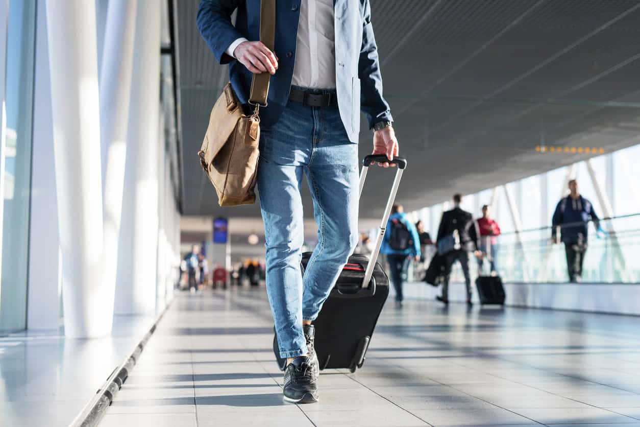 Business traveler walking through an airport terminal while pulling a rolling suitcase