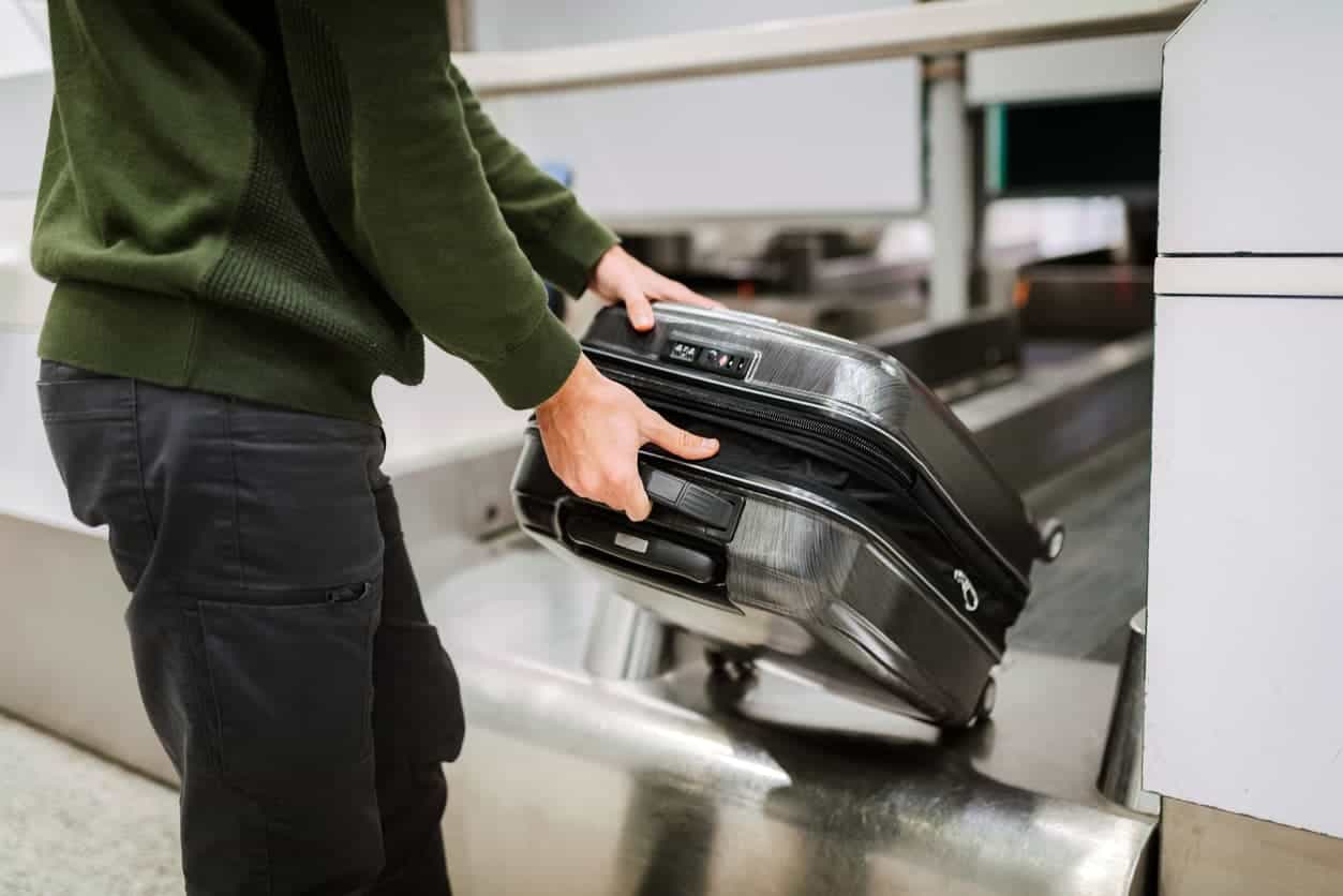Traveler checking in suitcase at airport baggage counter before flight