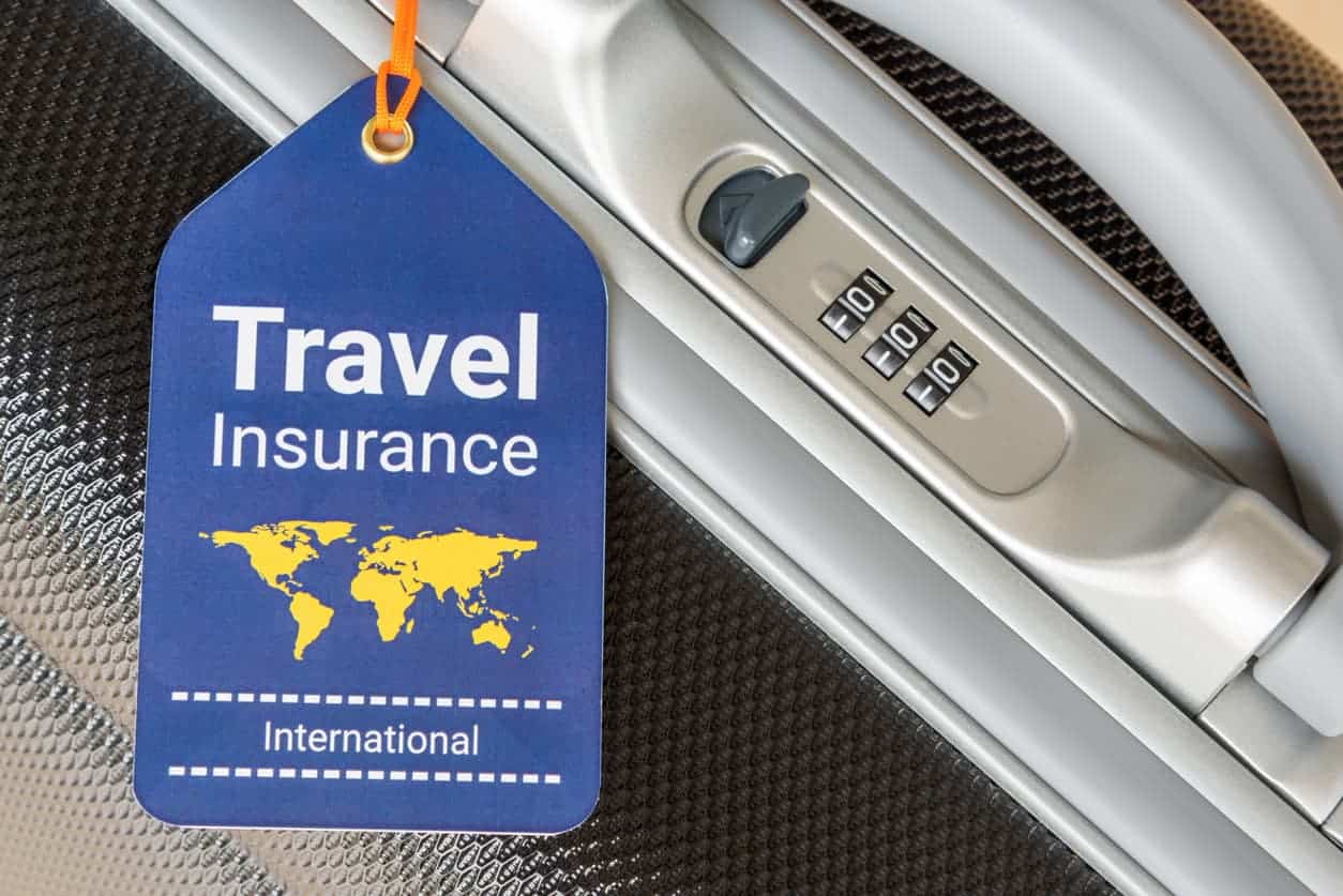 Travel insurance tag attached to suitcase handle with lock for international trips