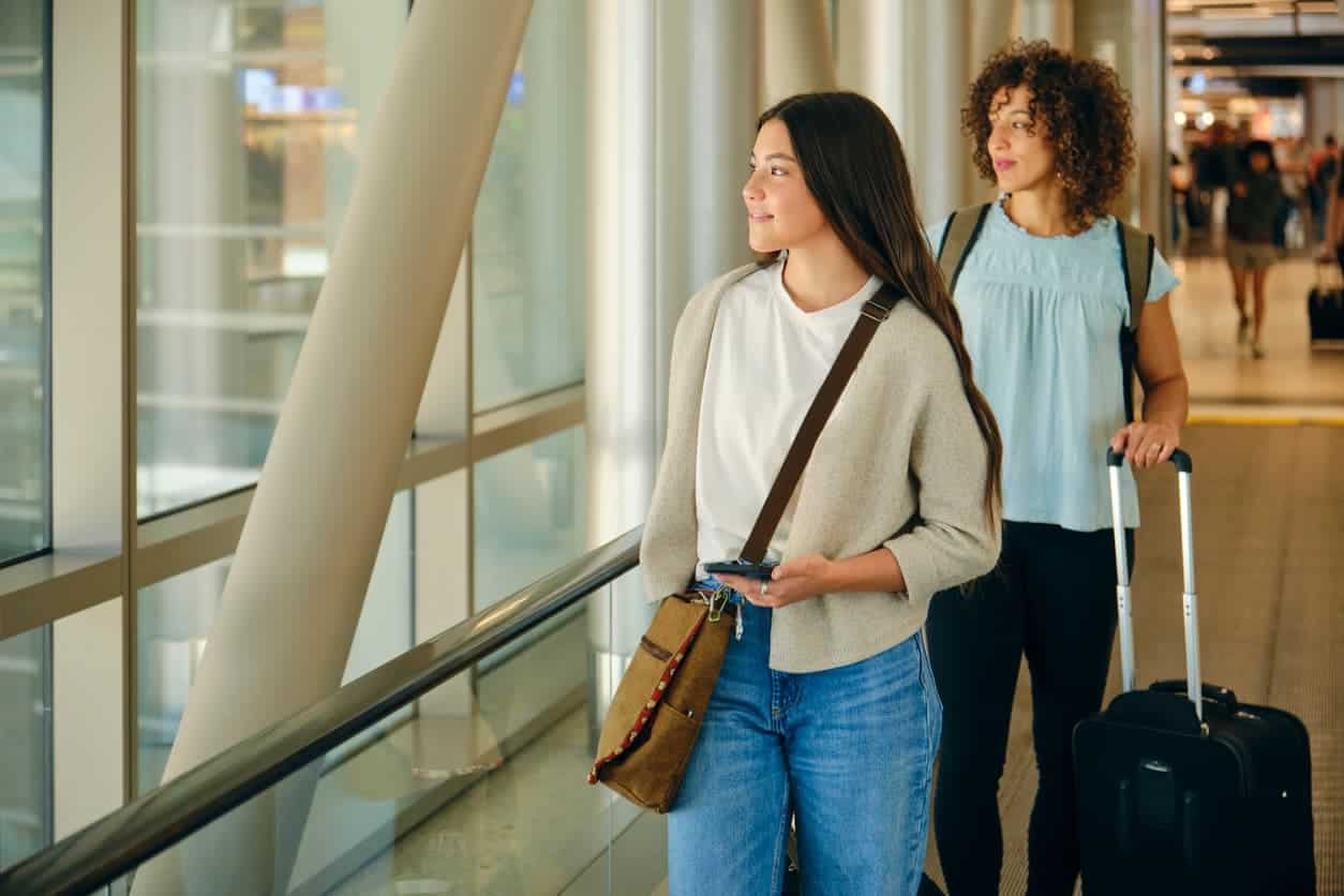 Women at the airport with luggage, ready to travel using rewards points for flights.