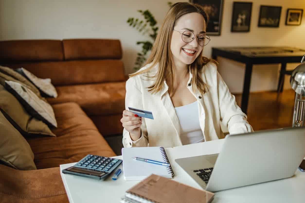 Woman using credit card on laptop while managing rewards points for online shopping