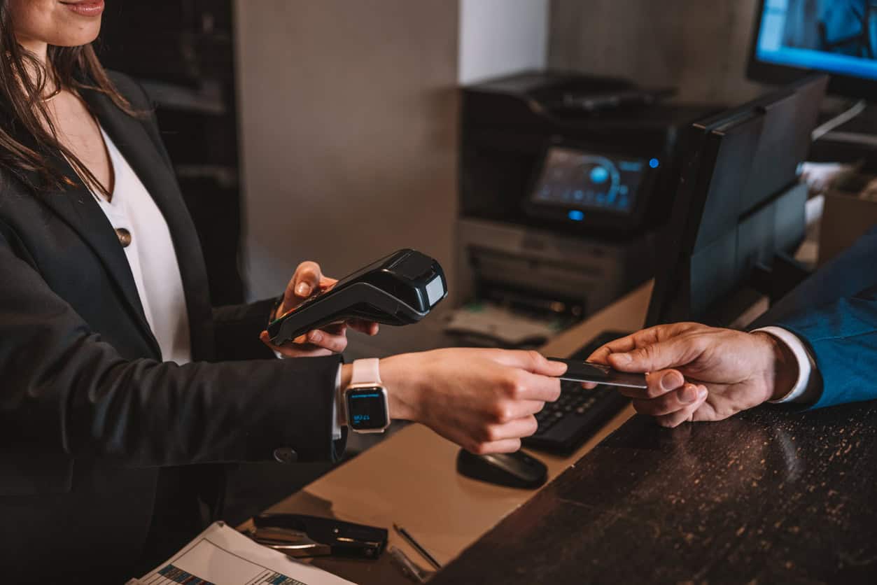Businessman paying for his stay at hotel reception desk using credit card