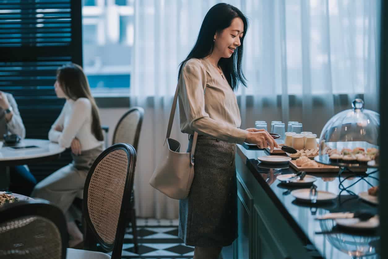 woman selecting food at buffet counter inside airport lounge