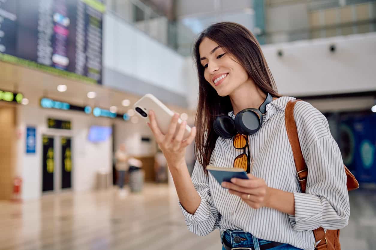 Traveler at the airport checking a mobile boarding pass after booking a flight through an online travel portal