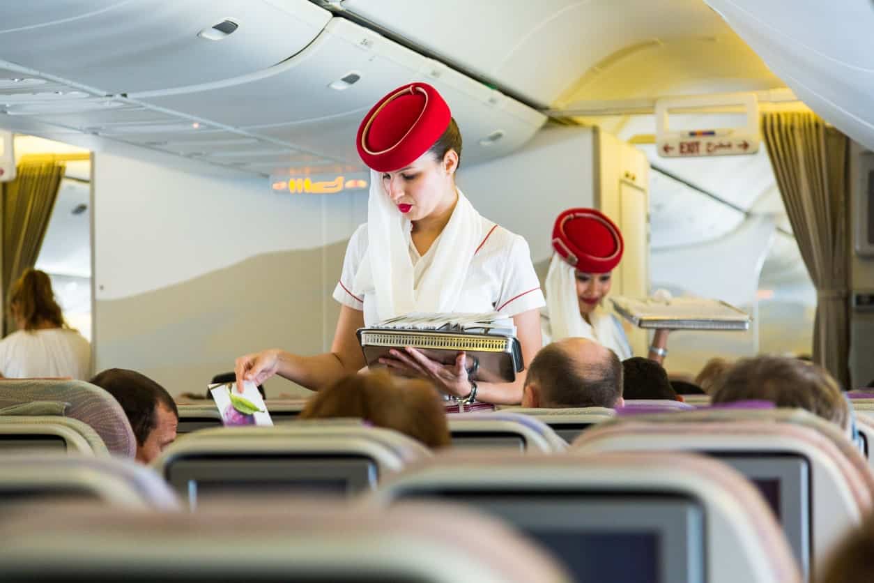 Emirates Airlines flight attendant assisting passengers