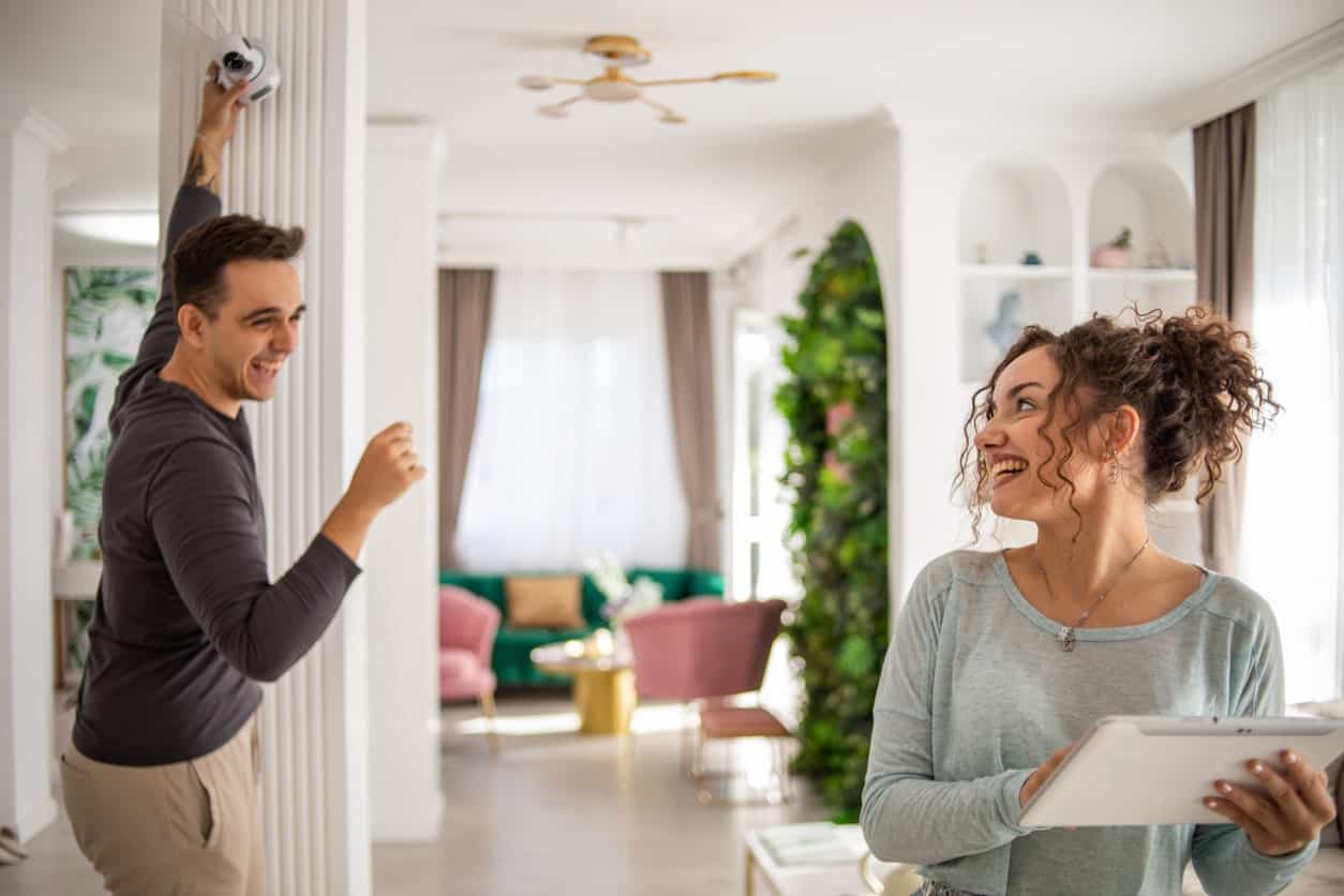 Couple sets up a new home security camera in their modern living room.