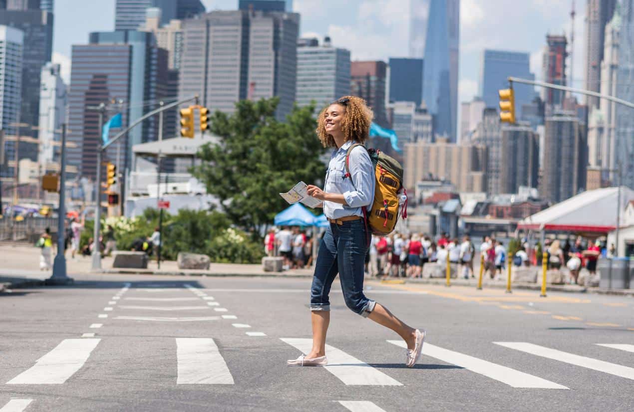 Woman holding a map while crossing a street in New York City.