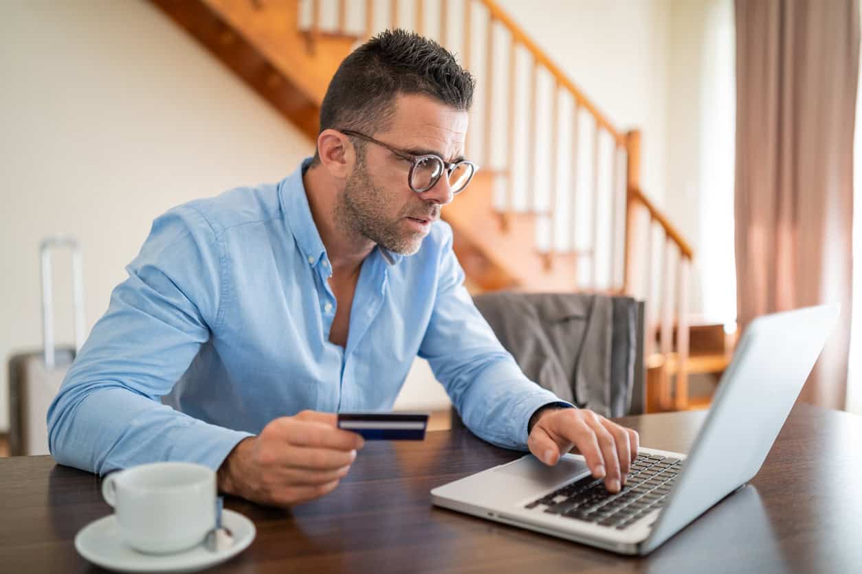 Man checking credit card information on his laptop at home.