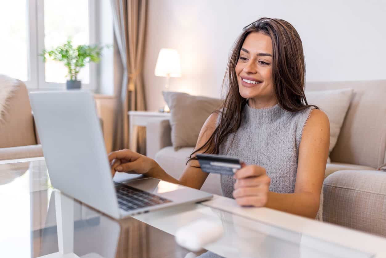 Woman using a credit card to book travel online with her laptop.