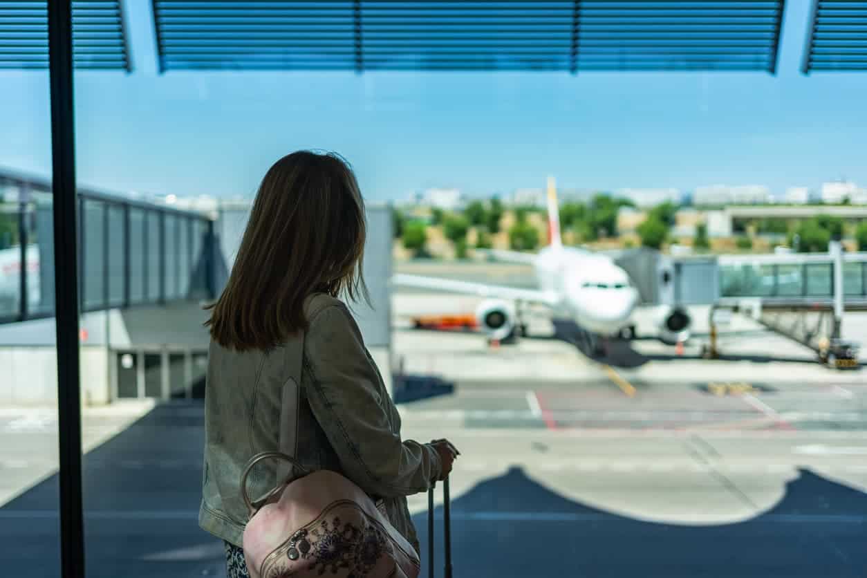 Traveler with luggage looking at Iberia airplane boarding gate before business class flight