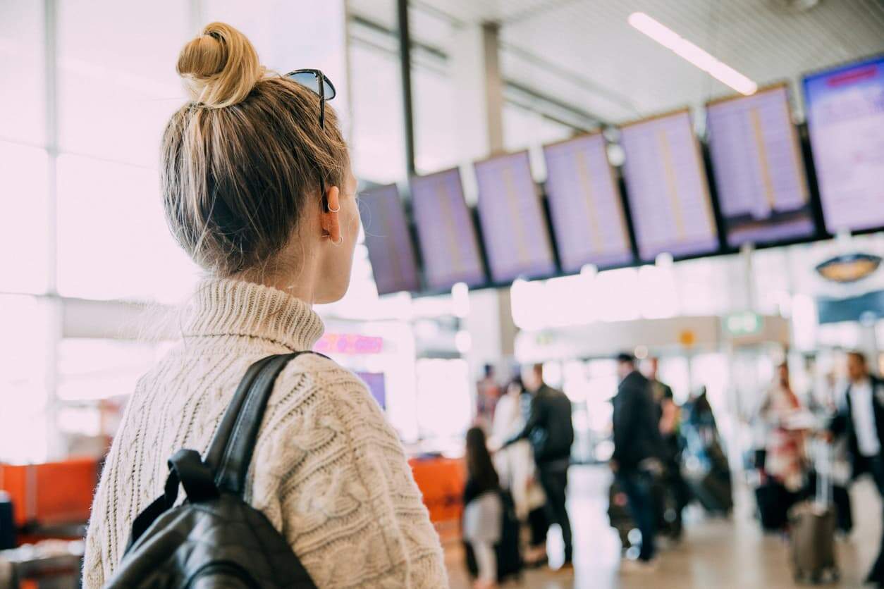 Traveler at airport checking flight information board before KLM business class flight