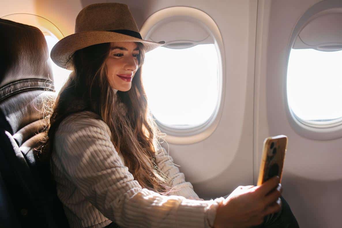 Woman taking a selfie while seated by the airplane window.