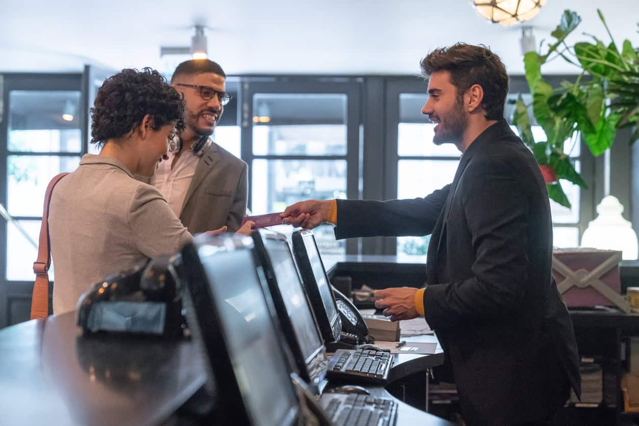 Guest checks in at a hotel front desk with a generic payment card.