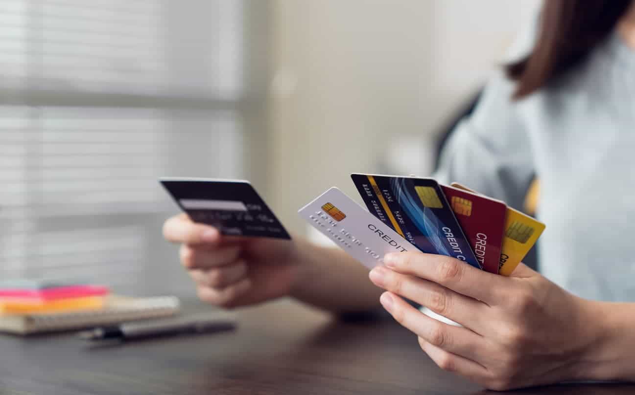 Person comparing multiple credit cards to choose the best one for travel rewards