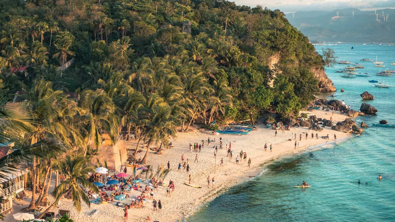 Aerial view of Boracay beach in the Philippines with tourists enjoying the sunset.
