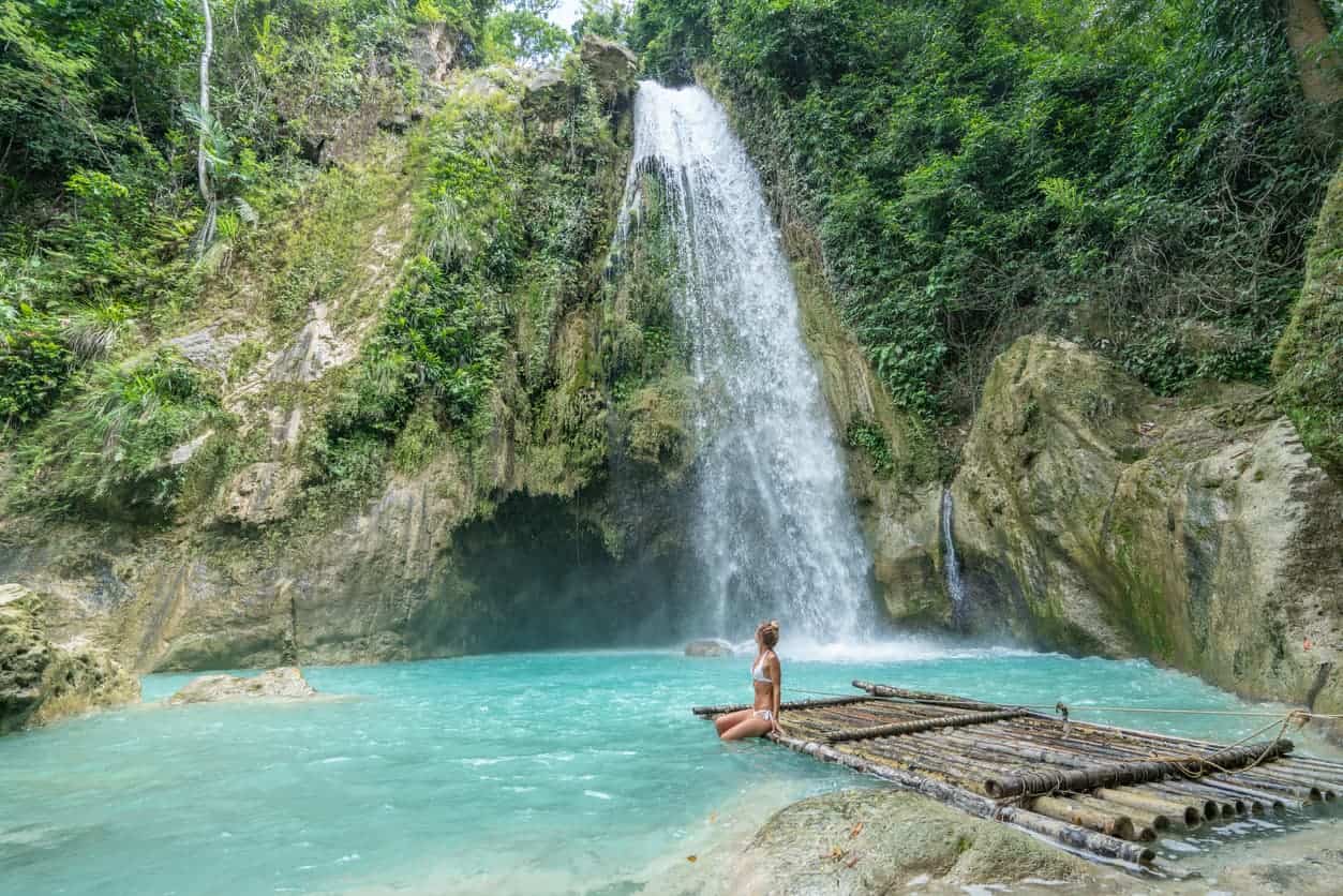 Woman sitting on a bamboo raft at Kawasan Falls in Cebu, Philippines.