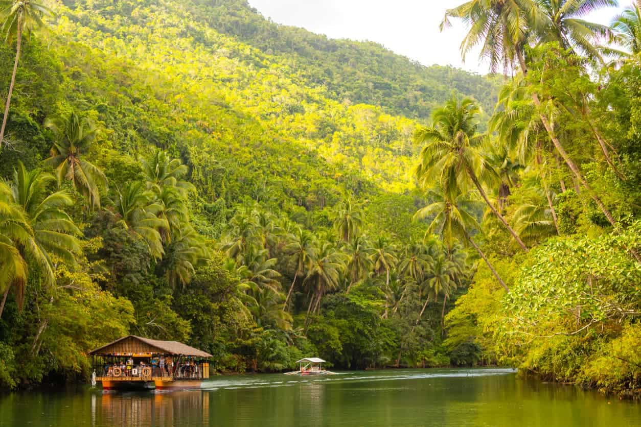 Tourist river cruise boat along the Loboc River surrounded by tropical palm trees in Bohol, Philippines