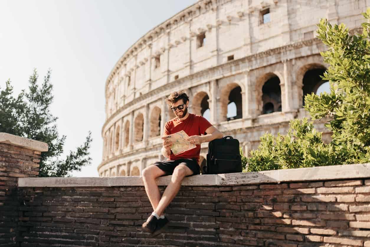 Young tourist reading a map in front of the Colosseum in Rome, Italy