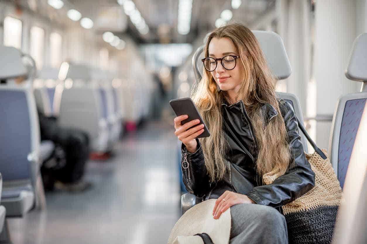 Woman sitting on a train checking her smartphone while traveling