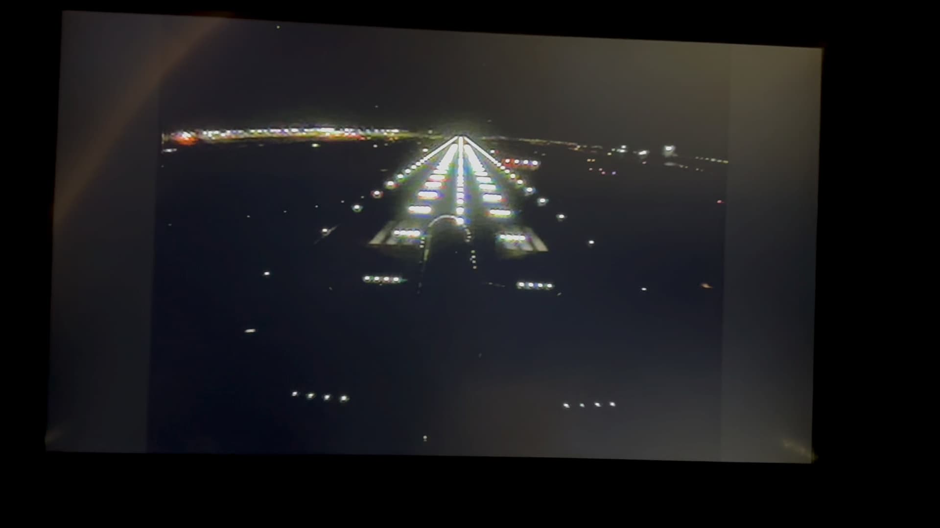 Airplane night landing view showing illuminated runway approach lights