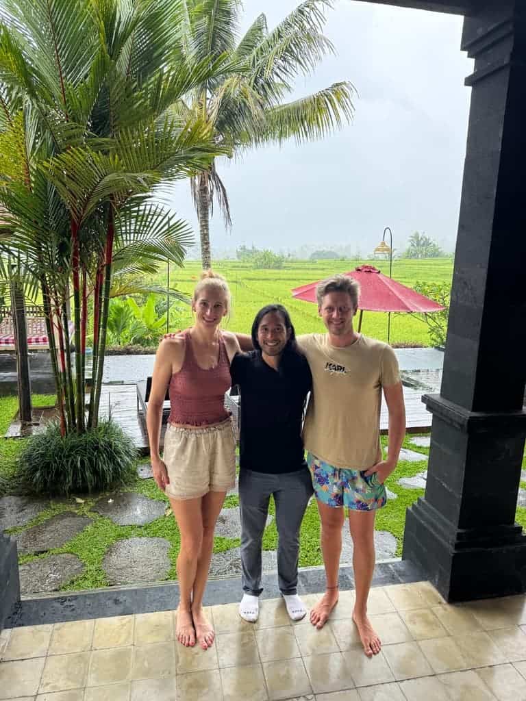 Guests posing together at a Bali homestay with lush rice fields and palm trees in the background
