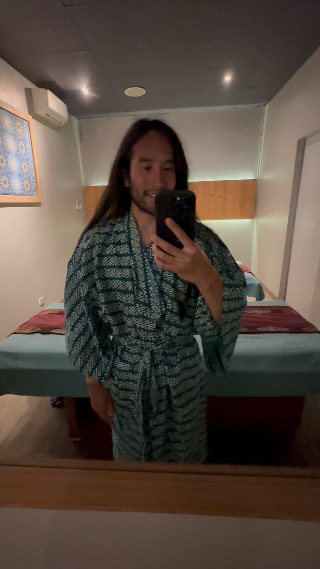Person wearing a robe taking a mirror selfie in a serene Bali spa treatment room